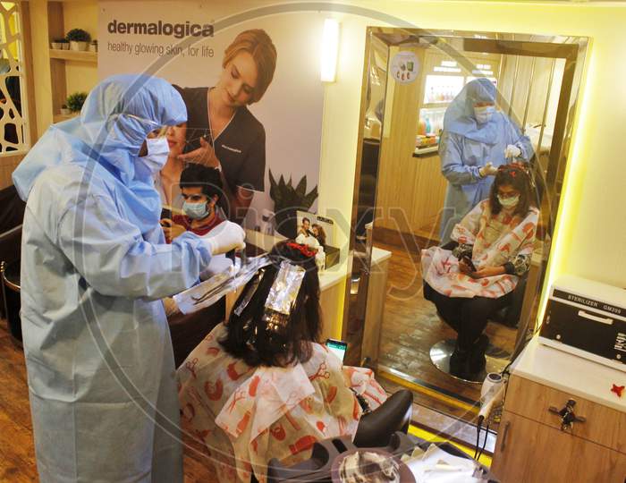 Hair stylists wearing protective gear attend to a customer with face masks at a salon in Mumbai, India, on June 29, 2020.