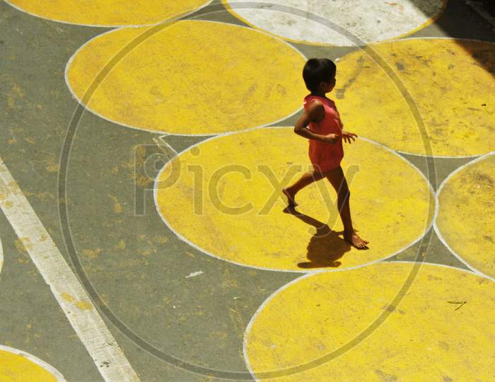 A kid runs on the yellow circles painted for physical distancing at a residential-cum-market area, in Mumbai, India on June 29, 2020.