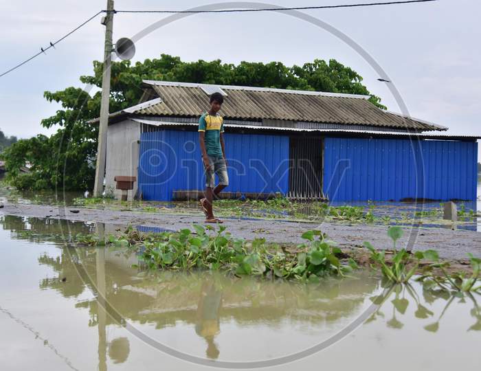 A Boy Walks Near A Partially Submerged Hut On Flood Waters At  Sildubi Village In Morigaon District Of Assam On June 29,2020