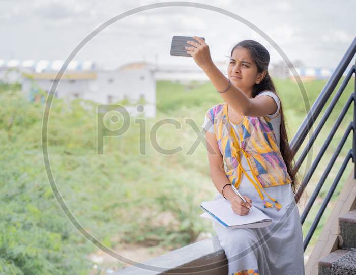 College Girl Outside Home Watching Online Class Due To Slow Internet Connection - Concept Of Network Issue At Remote Places And Problem Of Virtual Class Or Distance Learning During Pandemic.
