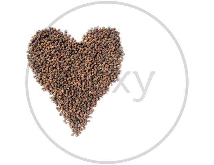 Dry Black peppercorns heap on white background top view heart shape.