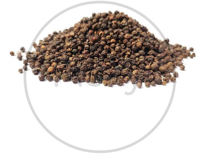 Dry Black peppercorns heap on white background sideview .