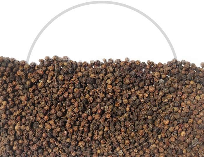 Dry Black peppercorns heap on white background top view cliping path.