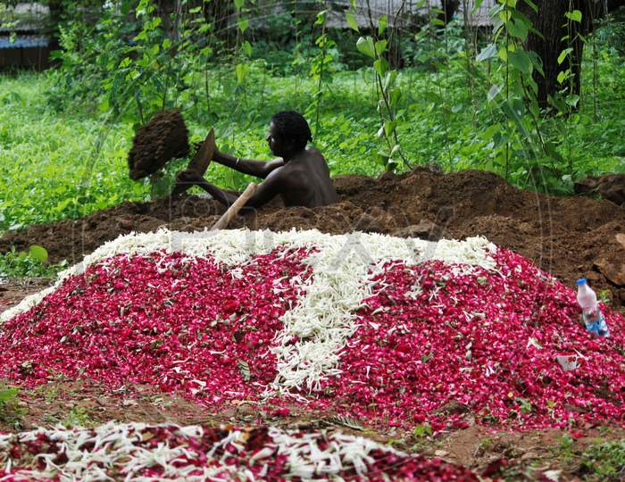 A gravedigger empties out mud, as he digs a grave for the burial of a person who died from the coronavirus disease (COVID-19), at a cemetery in Mumbai, India June 27, 2020.