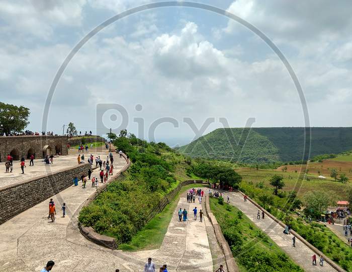 Mandav, Madhya Pradesh, India- July 14, 2019: Spiral Concrete Road to Enter In Rani Rupmati Mahal/Pavilion At Mandu. People Are Coming To Visit This Heritage Place. A Flat Top Hill In The Background.