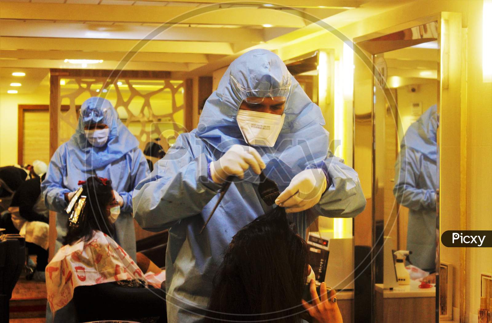 Hair stylists wearing protective gear attend to a customer with face masks at a salon in Mumbai, India, on June 29, 2020.