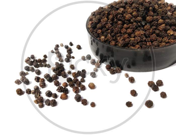 Dry Black peppercorns in bowl  on white background sideview .