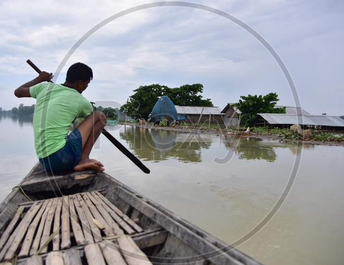 A Man Rows His Boat Near A Partially Submerged Hut On Flood Waters At  Sildubi Village In Morigaon District Of Assam On June 29, 2020.