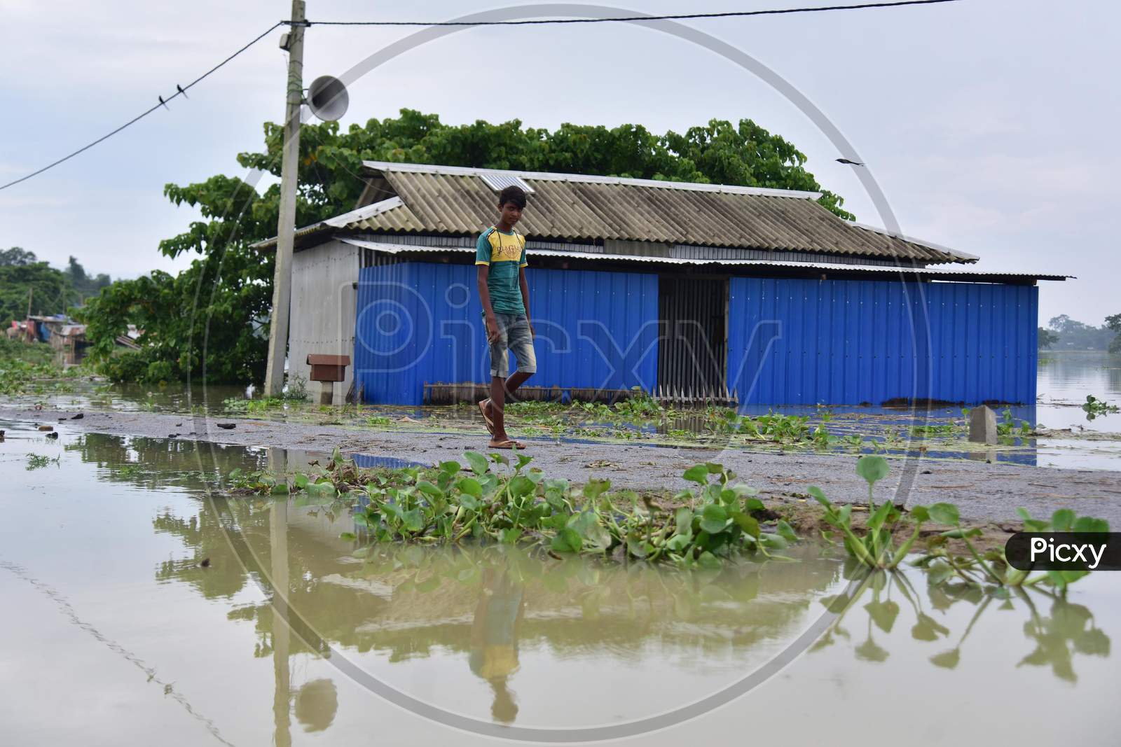A Boy Walks Near A Partially Submerged Hut On Flood Waters At  Sildubi Village In Morigaon District Of Assam On June 29,2020