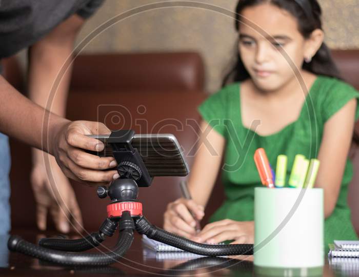 Father Helping Daughter By Adjusting Mobile To Studying The Lesson Of Online Class Or E-Learning - Concept Of Role Of Parent In Supporting Child During Virtual Class, Homeschooling, Distance Learning.