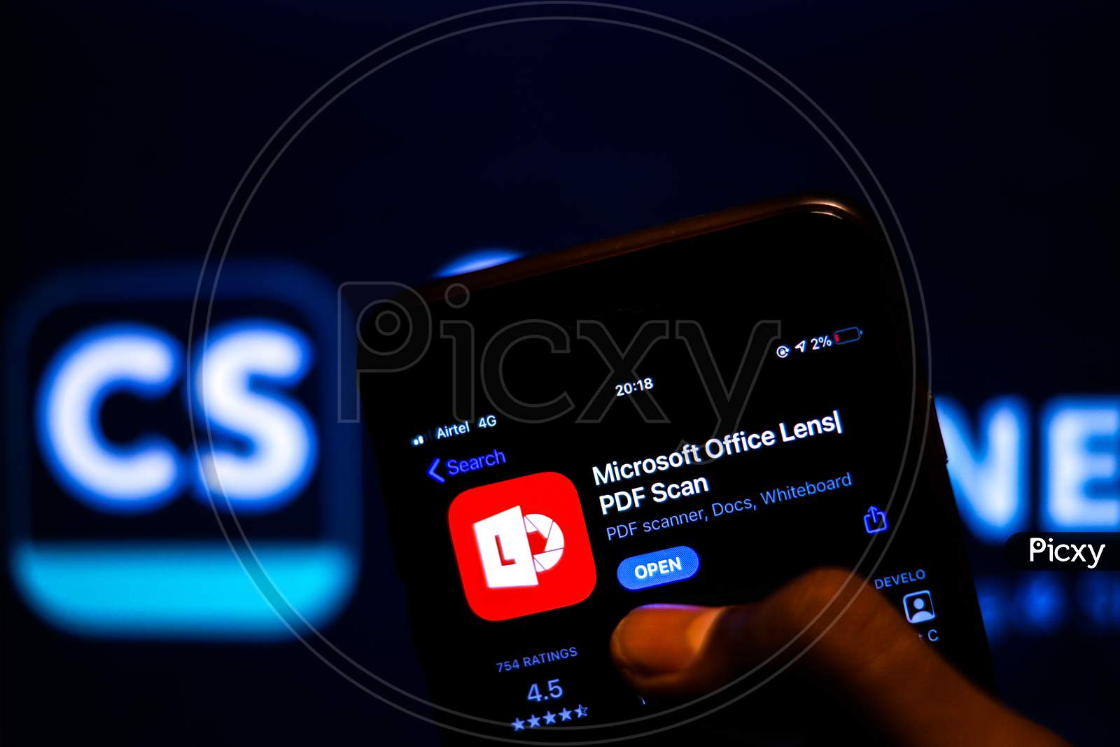 Microsoft Office Lens App on Mobile screen with Banned CamScanner Logo in the background and a finger about to Download