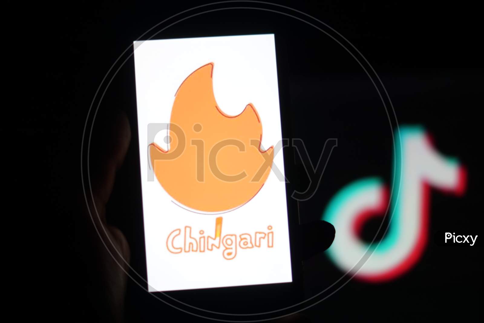 Chingari App logo on Mobile screen with Banned Tiktok Application Logo in the background