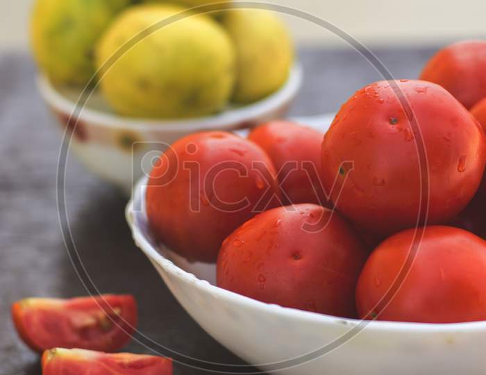 Red Organic Tomatoes And Limes In Blurry Background