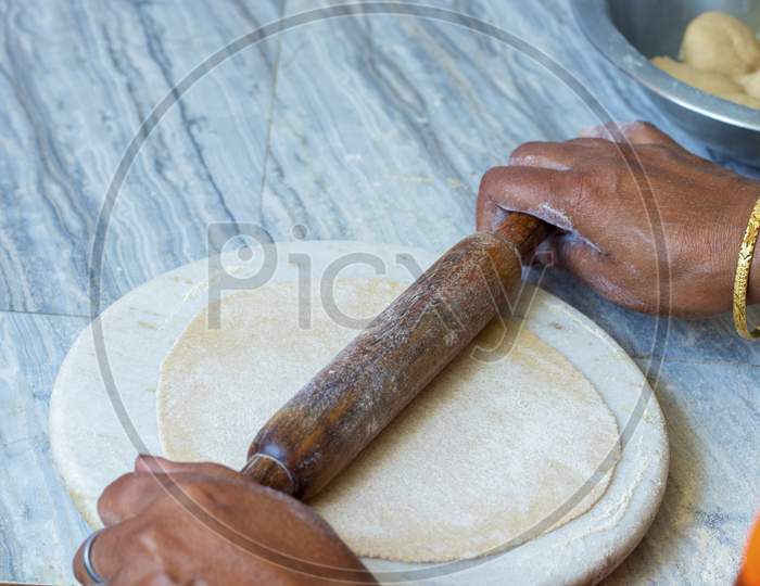 Indian woman making bread or roti by wheel roller.