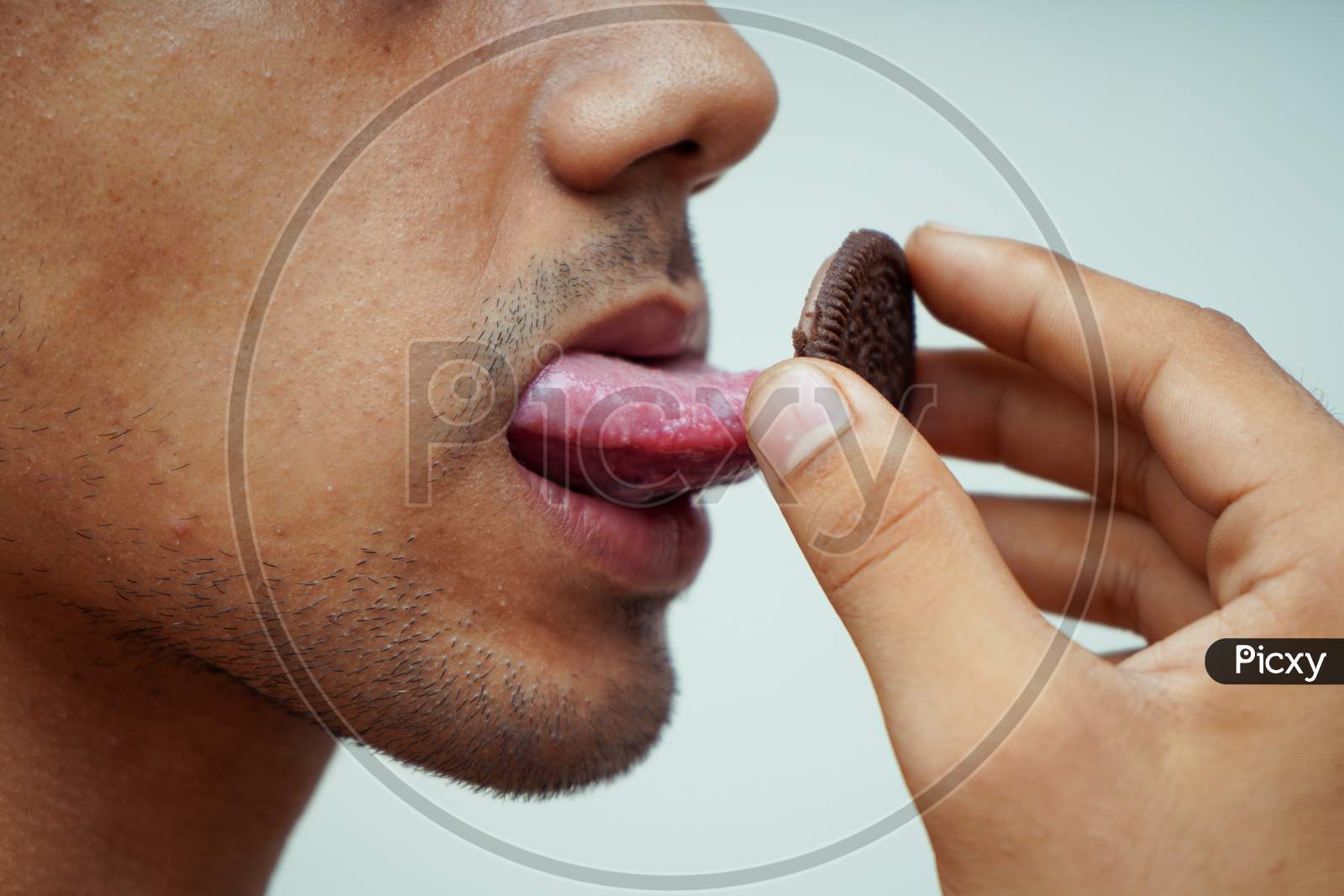 Image of Close Up Of A Man Licking Chocolate Biscuits-UV442657-Picxy