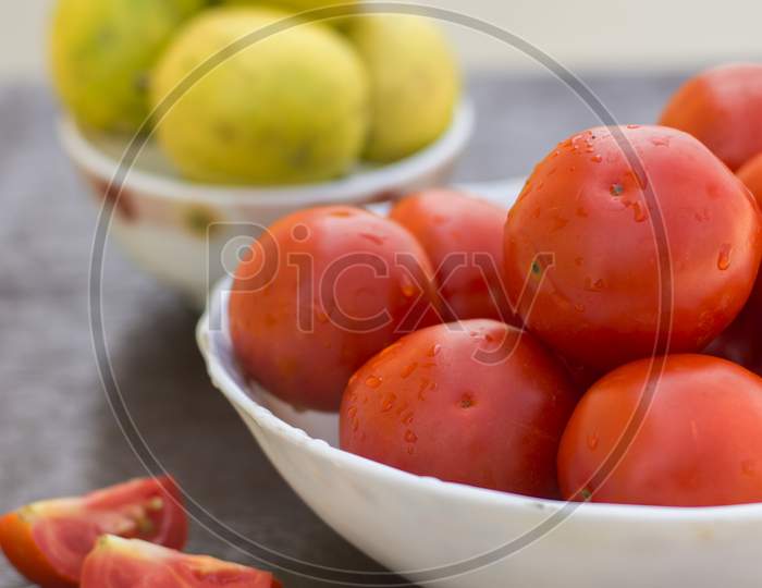 Red Organic Tomatoes And Limes In Blurry Background