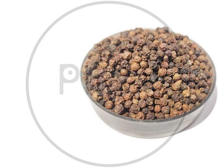 Dry Black peppercorns in bowl  on white background sideview .
