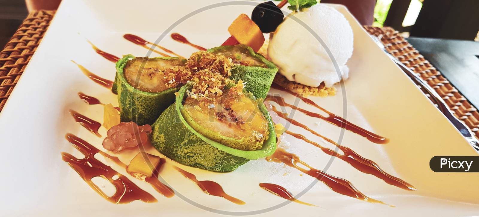 Fried Banana In A Green Pancake. A Scoop Of Ice Cream.