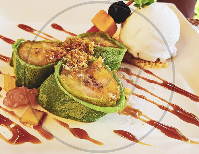 Fried Banana In A Green Pancake. A Scoop Of Ice Cream.