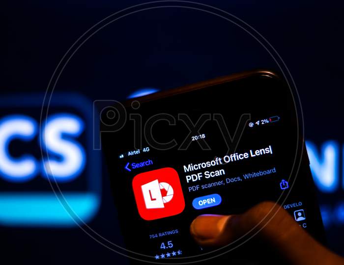Microsoft Office Lens App on Mobile screen with Banned CamScanner Logo in the background and a finger about to Download