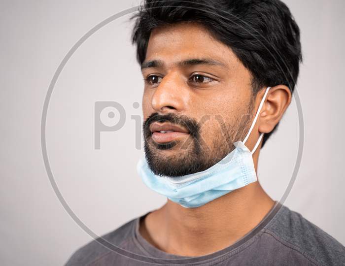 Concept Showing Of Improper Way Of Using Face Masks During Coronavirus Or Covid-19 Crisis - Young Man Wearing Medical At Neck On Isolated Background