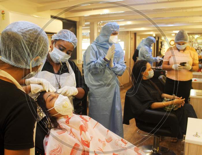 Employees wearing protective gear attend to a customer with face masks at a salon in Mumbai, India, on June 29, 2020.