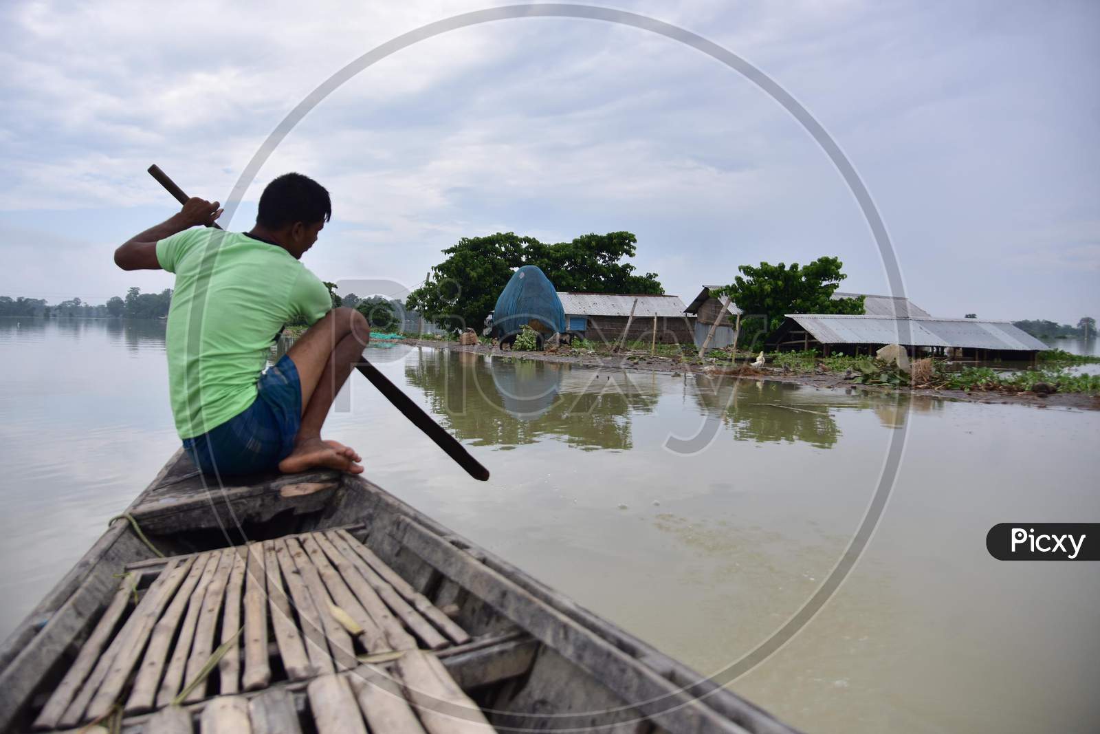 A Man Rows His Boat Near A Partially Submerged Hut On Flood Waters At  Sildubi Village In Morigaon District Of Assam On June 29, 2020.