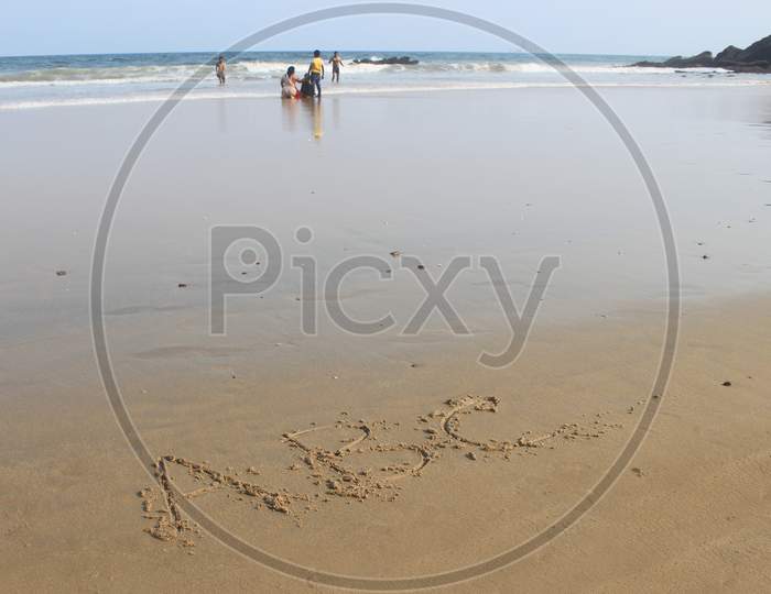 ABC written on a Beach Shore with People moving in the Background