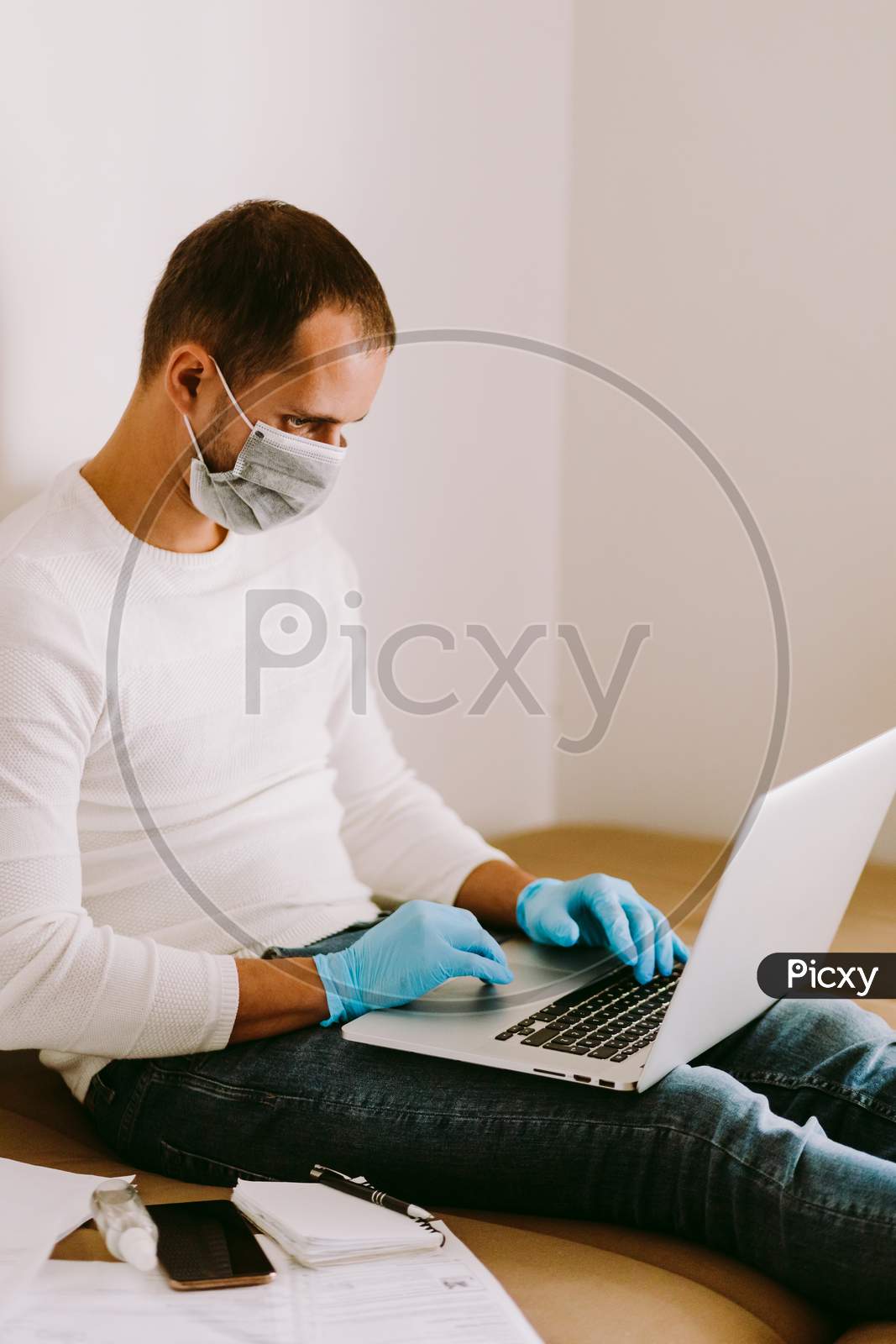 Man Working At Home Using Laptop And Smartphone During Quarantine
