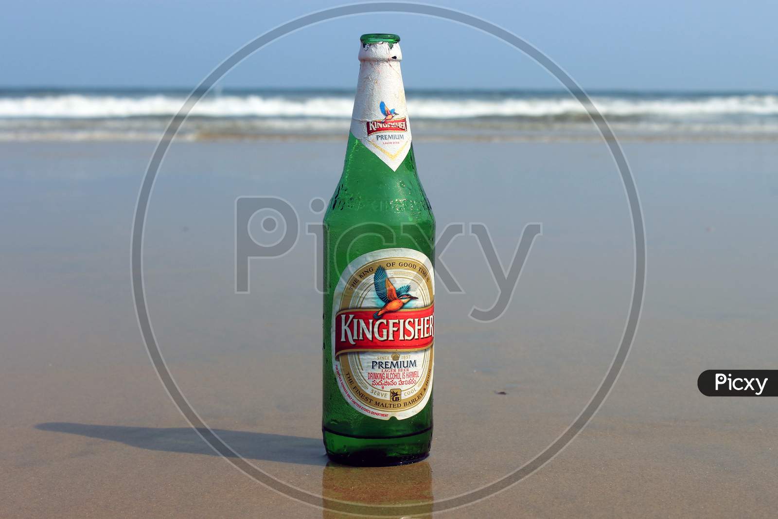 An Alcohol or Beer Bottle on a Beach Shore with Beach in the Background
