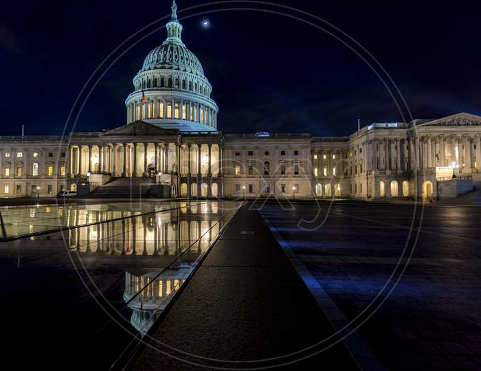 The capitol in Washington D.C., United States of America at a cold night in spring with reflections in water.