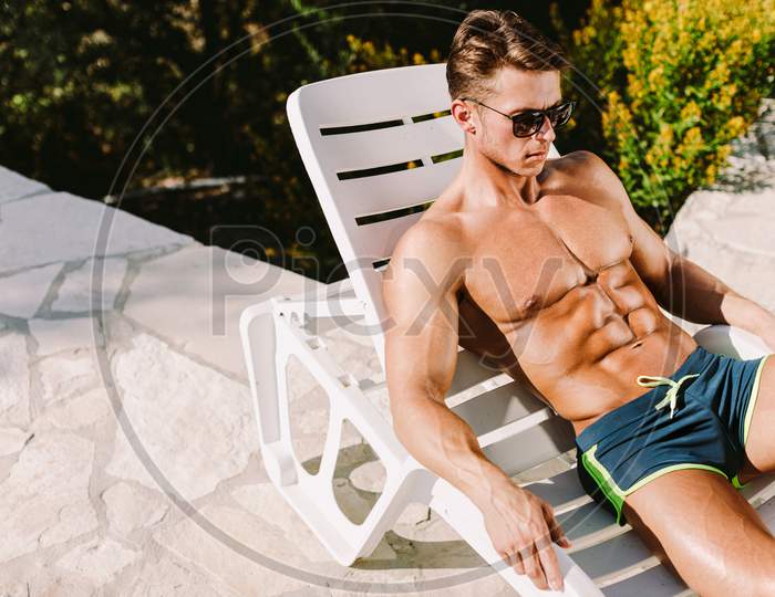 Handsome Muscular Man Sunbathe On Sunbed And Tanning