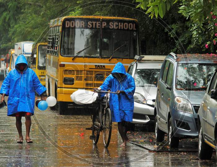 Men wearing raincoats walk on a street on a rainy day, after cyclone Nisarga made its landfall on the outskirts of the city, in Mumbai, India, June, 3, 2020.