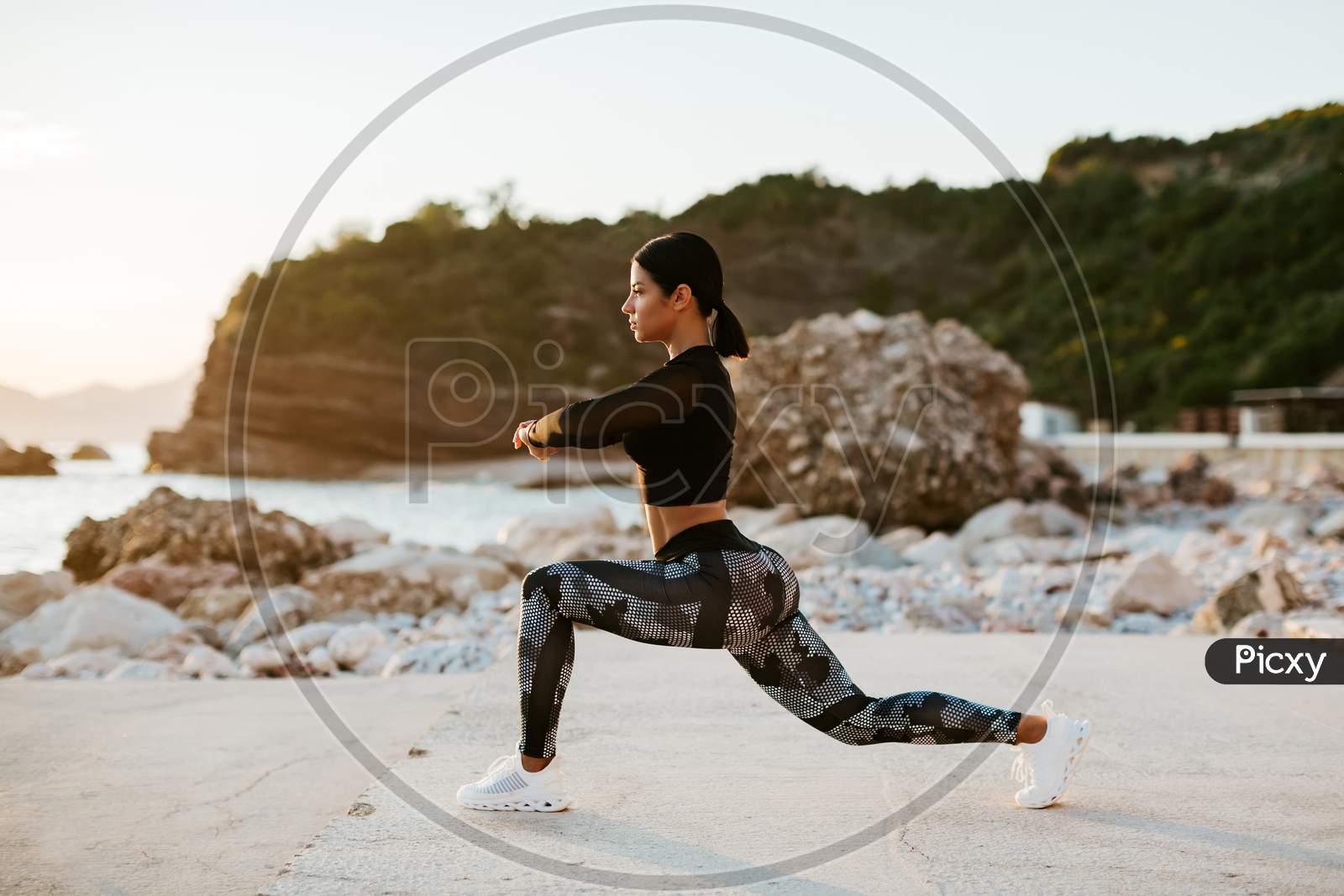 Sexy Athletic Woman Stretching Exercises On Beach At Sunset