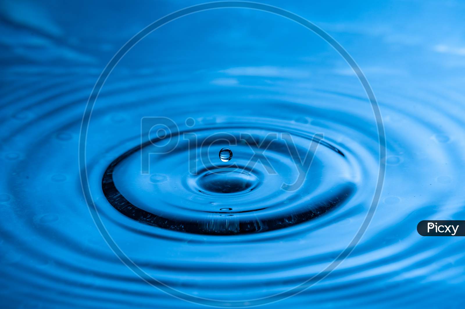 High Speed Water Drop Photography. Blue With Single Drop About To Splash