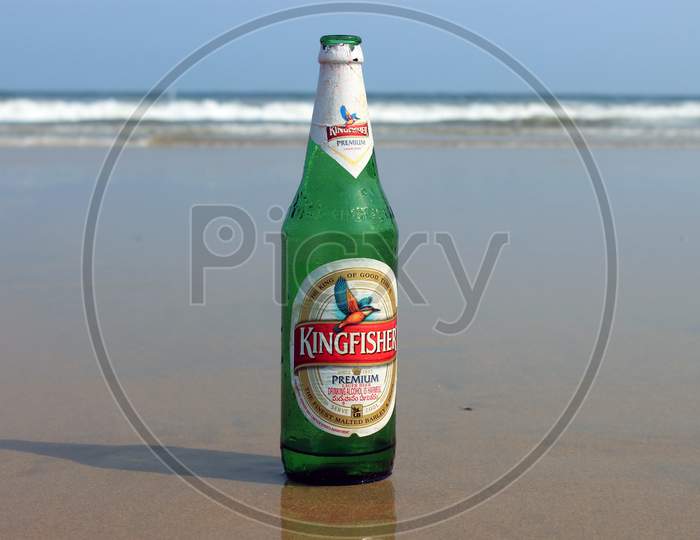 An Alcohol or Beer Bottle on a Beach Shore with Beach in the Background