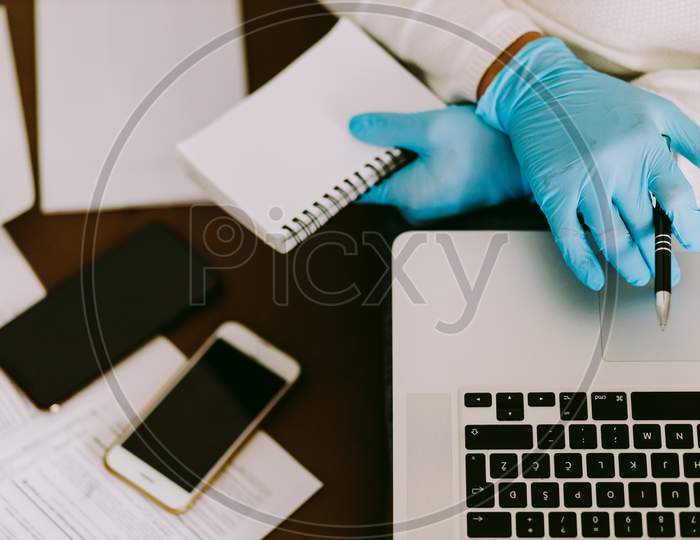 Man Working On Laptop And Wearing Latex Gloves For Virus Prevention