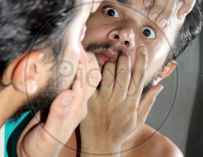 Young Man Checking His Eye On Mirror