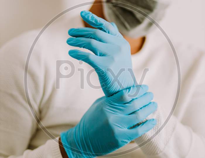 Man Using Latex Gloves At Home For Virus Prevention