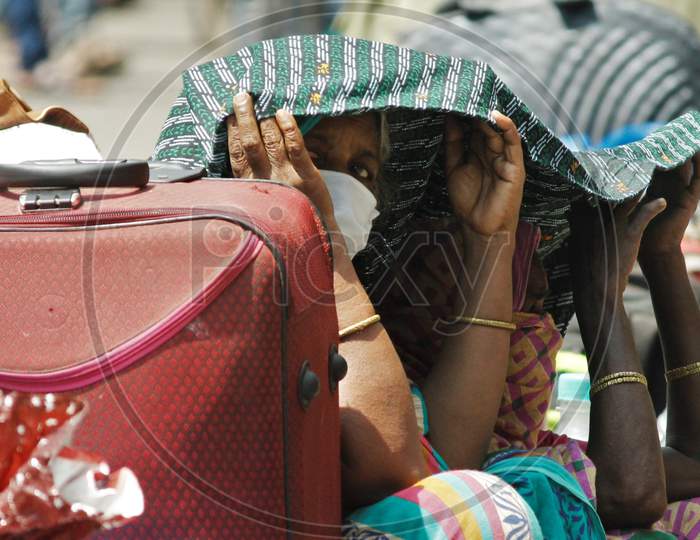 Women take shelter under a shawl as they wait outside Chhatrapati Shivaji Maharaj Terminus(CSMT) in scorching heat to board a train that will take them to their home state during an extended lockdown to slow the spreading of the coronavirus disease (COVID-19), in Mumbai, India on May 27, 2020.