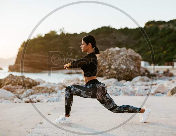 Sexy Athletic Woman Stretching Exercises On Beach At Sunset