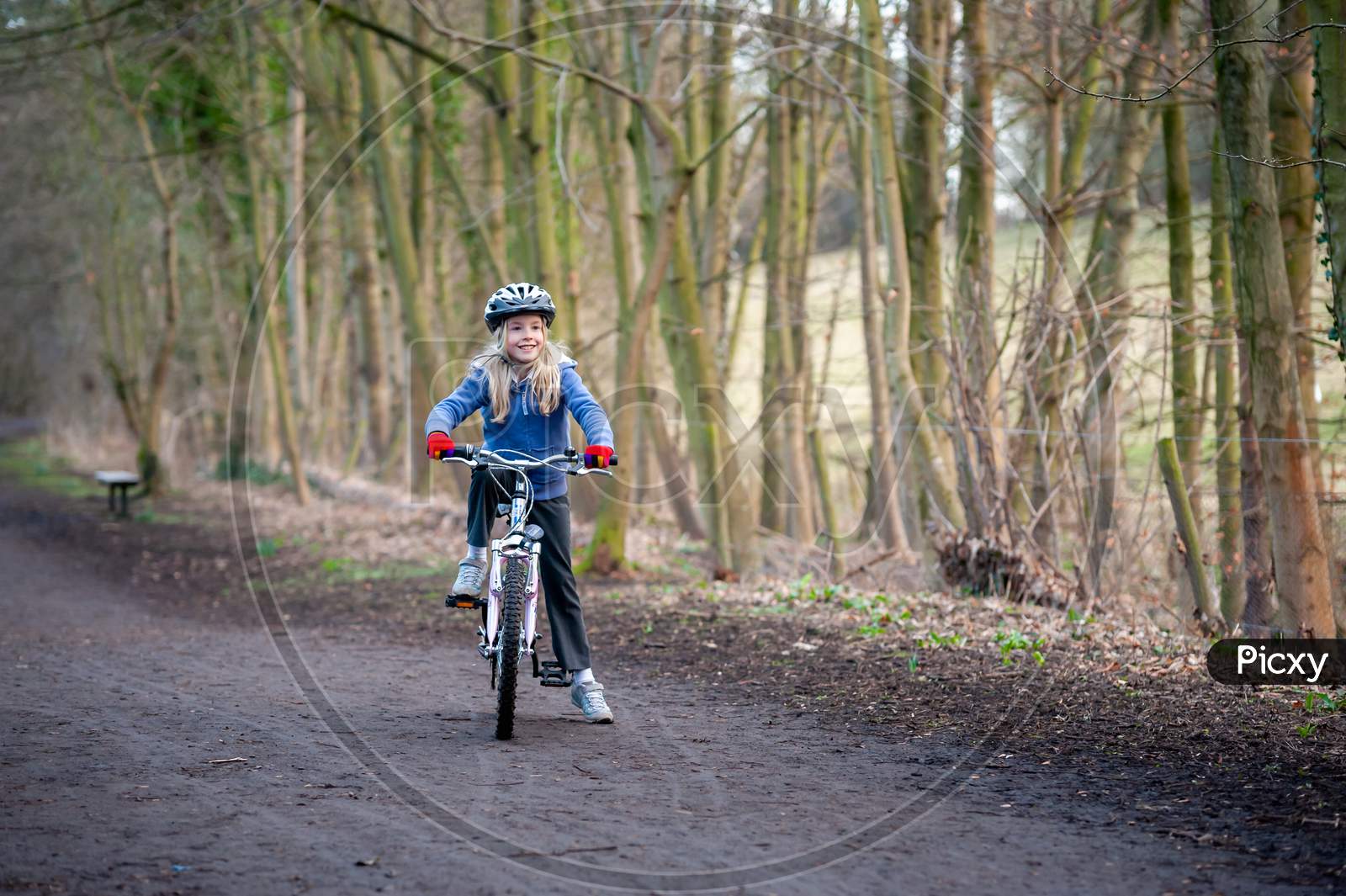 Smiling, Happy Young Blonde Girl Paused On Her Bike On A Country Path