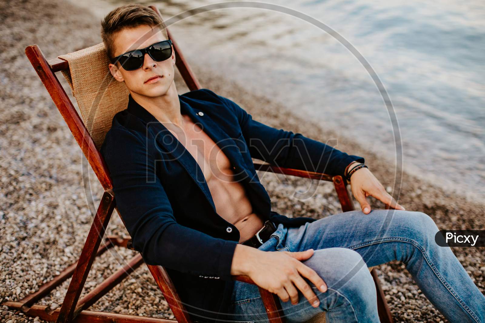 Stylish Muscular Handsome Man Wearing Jacket And Sunglasses Relax At Seaside