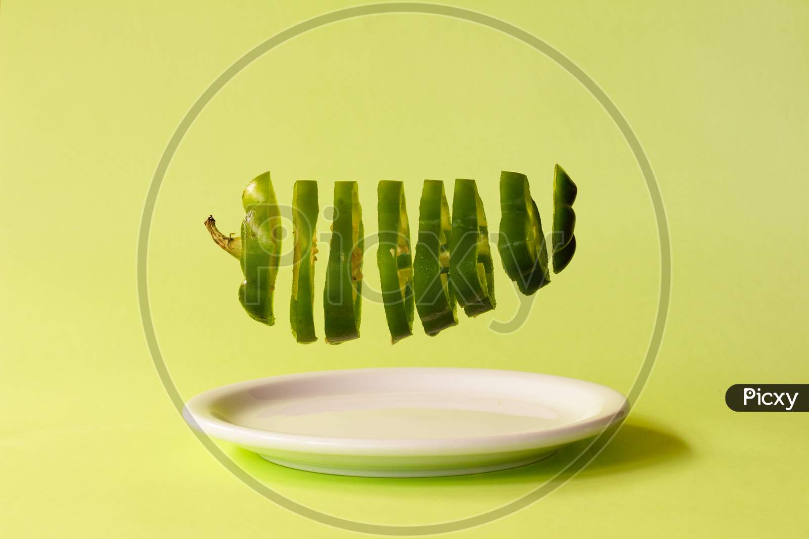 Green Bell Pepper Cut Into Slices Suspended A Plate. Healthy Food Concept.