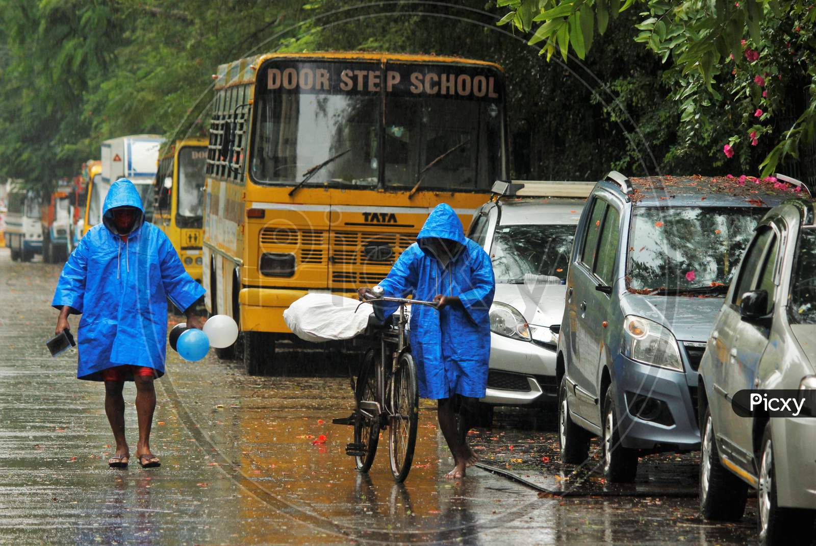 Men wearing raincoats walk on a street on a rainy day, after cyclone Nisarga made its landfall on the outskirts of the city, in Mumbai, India, June, 3, 2020.