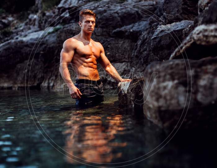 Handsome Muscular Man Standing Wet  In Water Wearing Jeans