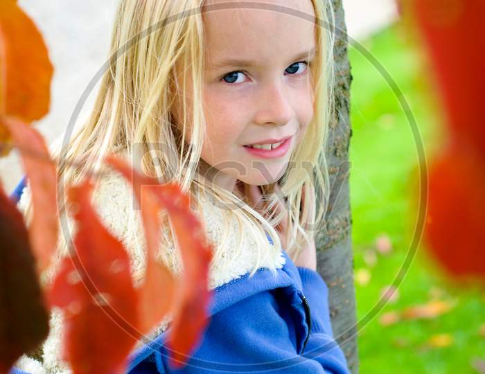 Pretty Young Blonde Girl Through Autumn Foliage