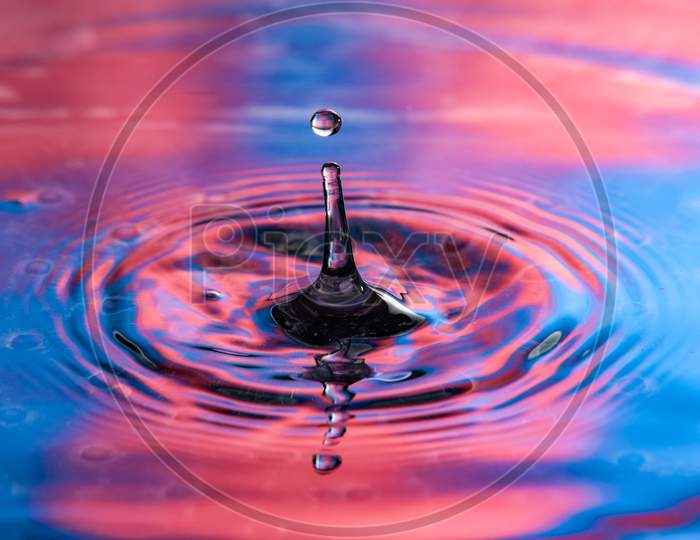 Single Water Drop At Top Of Splash. Vibrant Red And Blue Colours, High Speed Water Drop Photography