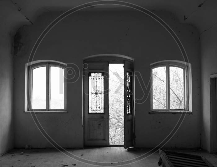 Abandoned Room With Door And Two Windows