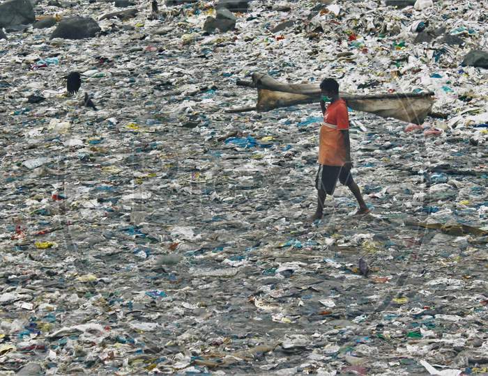 A fisherman walks on a beach covered with plastic waste to go to the sea to wash a cloth used to cover boats on the occasion of World Environment Day, in Mumbai, India on June 5, 2020.